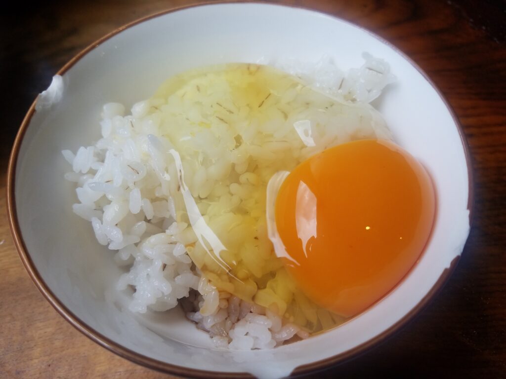 地鶏食堂の麦ごはんに生卵がかかっている画像